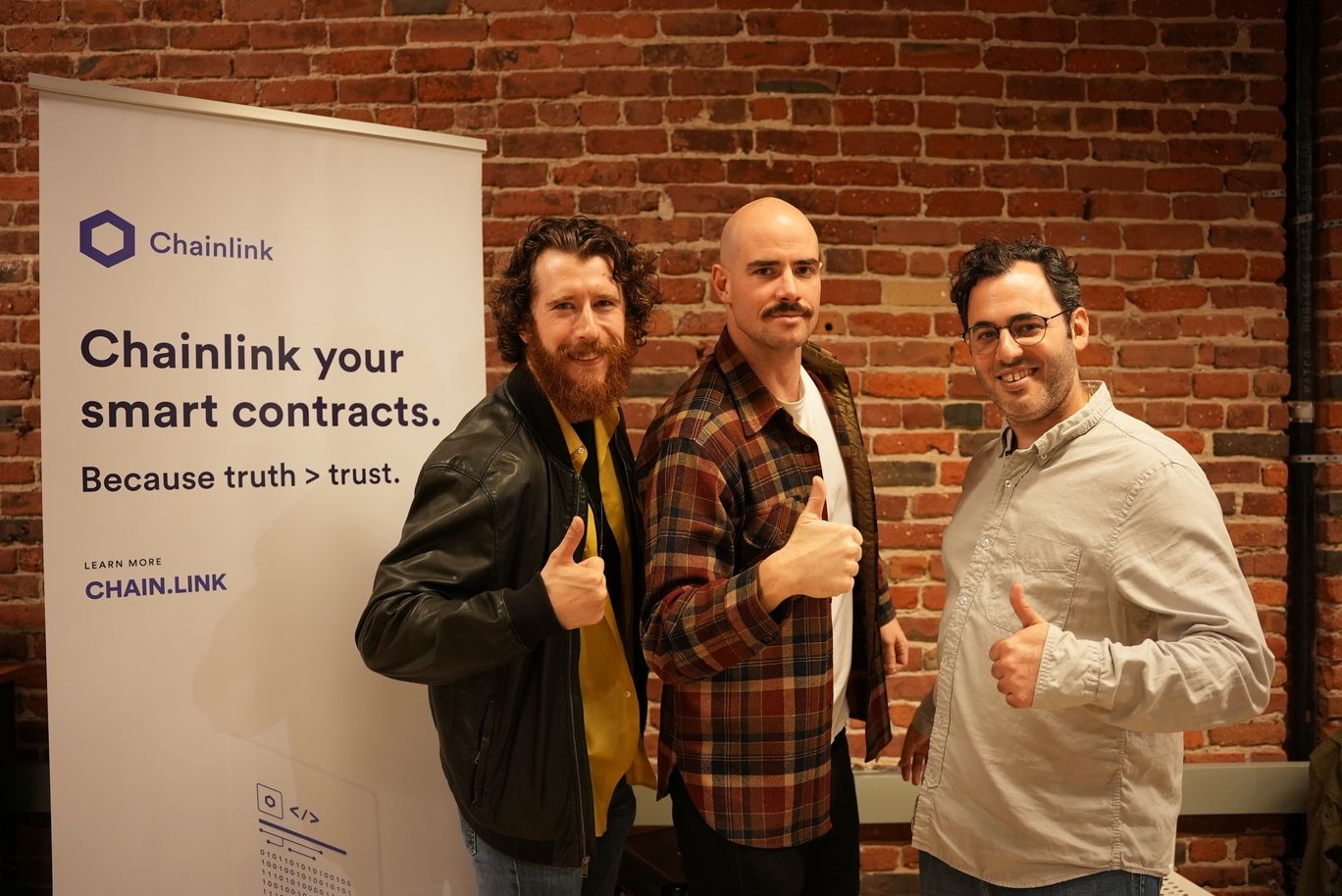 Three men give the 'thumbs up' sign at the Chainlink + IoTeX event